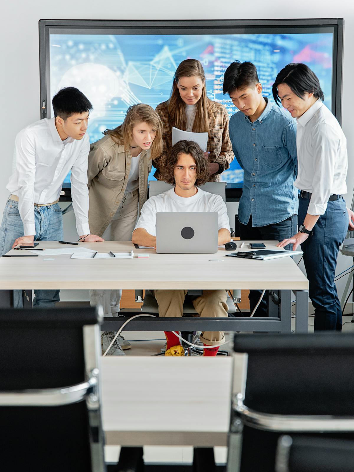 Office team collaborating around a laptop in a modern workplace